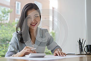 Young asian business woman sitting at her workplace and reading financial document