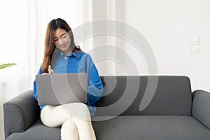 Young asian business woman work from home with laptop computer online to internet on sofa, freelance girl using notebook