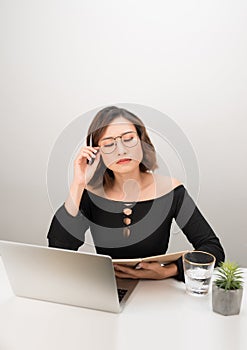 Young asian business woman thinking daydreaming sitting at desk with laptop computer