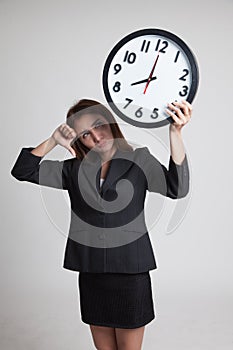 Young Asian business woman thumbs down with a clock.