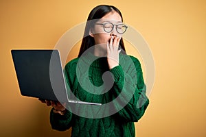 Young asian business woman wearing glasses and working using computer laptop bored yawning tired covering mouth with hand