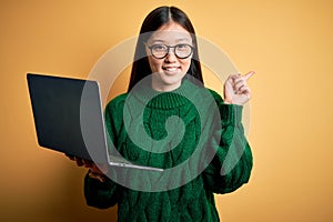 Young asian business woman wearing glasses and working using computer laptop cheerful with a smile on face pointing with hand and