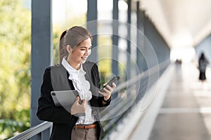 Young Asian business woman wearing suit using application on cell phone, read news on smartphone, fast connection
