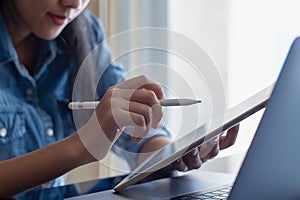 Young asian business woman working on digital tablet pc with laptop computer .