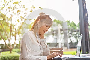 Young asian business woman working in office using laptop computer and digital tablet.