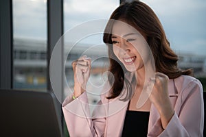 young Asian business woman working overtime on laptop in evening at office