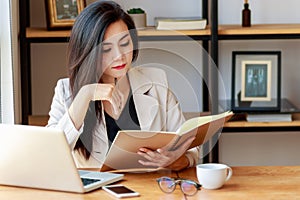 Young Asian business woman working at workplace. beautiful Asian woman in casual suit working with reading book