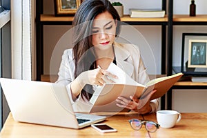 Young Asian business woman working at workplace. beautiful Asian woman in casual suit working with reading book,