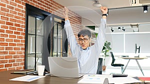 Young asian businessman arms up with happiness while looking at laptop computer at office, Asia office man celebration after