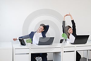 Young Asian businessman and businesswoman relaxing stretching arms, head and hands after work with laptop for a long time