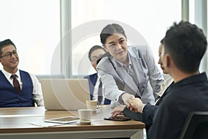 young asian businessman and businesswoman shaking hands during meeting