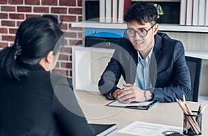 Young asian businessman and businesswoman talking about business agreement at meeting table in modern office.business partnership