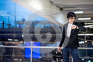 Young asian businessman checking the time in airport terminal