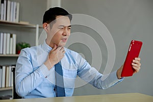 Young asian businessman complaining about pain and a sore throat during an online video call