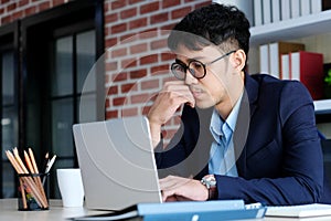 Young asian businessman concentrate on working with laptop computer at office, business people and office lifestyle concept