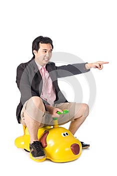 Young Asian businessman driving a baby toy car look like dog, is