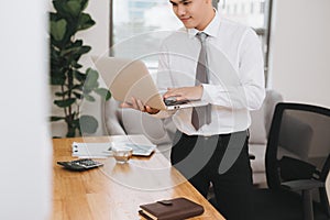 Young asian businessman holding a laptop pc