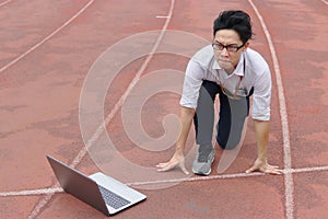 Young Asian businessman with laptop ready start position to forward on race track. Competition and vision business concept