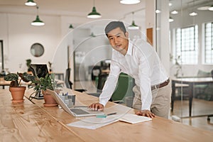 Young Asian businessman leaning on his desk using a laptop