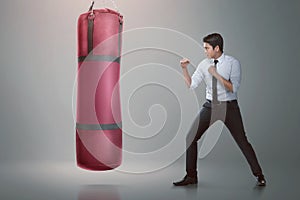 Young asian businessman punching boxing bag