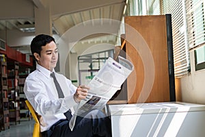 Young Asian businessman reading a newspaper