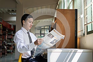 Young Asian businessman reading a newspaper