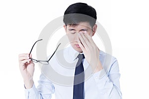 Young Asian businessman rubbing his tired eyes from long hours of works using computer