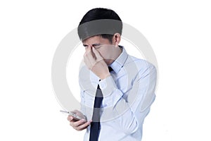 Young Asian businessman rubbing his tired eyes from long hours of works using smart phone