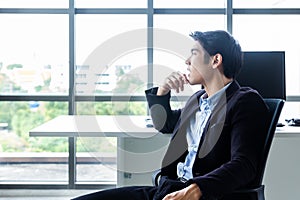 Young Asian businessman Sitting in a modern office is thinking and analyzing to find solutions to improve business performance