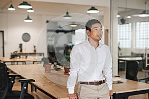 Young Asian businessman standing in an office deep in thought