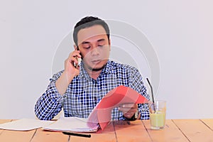 Young Asian businessman talking on the phone-checking some document file data