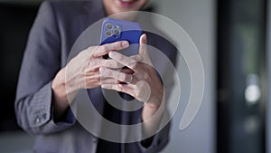 Young Asian businessman typing messages or reading news on his smartphone