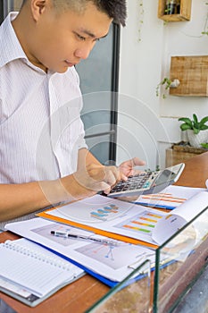 Young Asian businessman using calculator