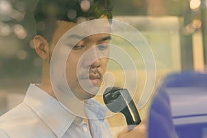 Young Asian businessman using the payphone outdoors