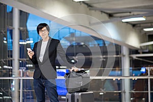 Young asian businessman using smartphone in airport terminal