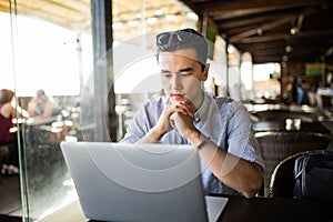 Young asian businessman working with laptop computer and notebook in cafe casual entrepreneur. Freelance work