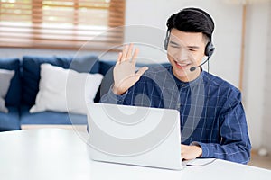 Young asian businessman working on laptop computer wearing headphone at home.