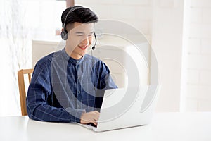 Young asian businessman working on laptop computer wearing headphone at home.