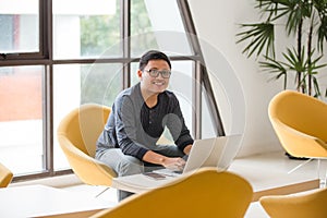 Young Asian businessman working on laptop in modern office.