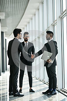 Young asian businesspeople shaking hands and smiling in modern office building