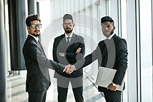 Young asian businesspeople shaking hands and smiling in modern office building