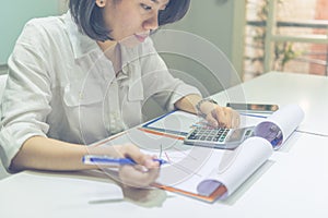 Young Asian businesswoman calculate sales on calculator