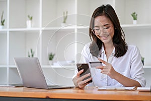 Young Asian businesswoman enjoy shopping online using credit card at a coffee shop.