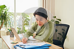 Young Asian businesswoman focusing on her documents