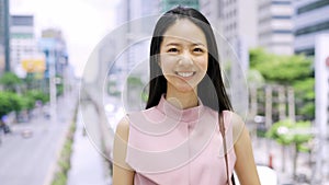 Young Asian businesswoman looking at camera and smile the urban city office buildings. Chinese Korean Asia smart lady