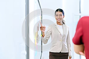 Young Asian businesswoman manager pointing finger at paperwork, pie chart diagram document on glass board in the office. Looking