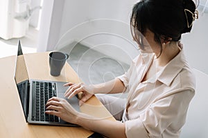 Young asian businesswoman sitting front open portable laptop computer reading email from client, long hours of work