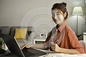 Young Asian businesswoman sitting at home working on laptop computer. Asian woman studying online using laptop surfing information