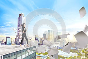 Young asian businesswoman standing with flying paper on the rooftop of building