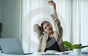 Young Asian businesswoman stretching arms raised relaxing at the office.